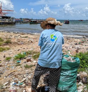Hier sieht man, wie eine Frau unseres Projektpartners TonToTon bei einem Beach-Clean-up den Strand in Kambodscha von Plastikmüll befreit und ihr Sammelsack bereits gut gefüllt ist